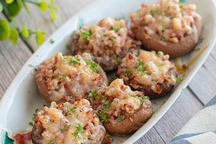 お皿に盛られたチーズとハーブがトッピングされた6つの焼きマッシュルーム。