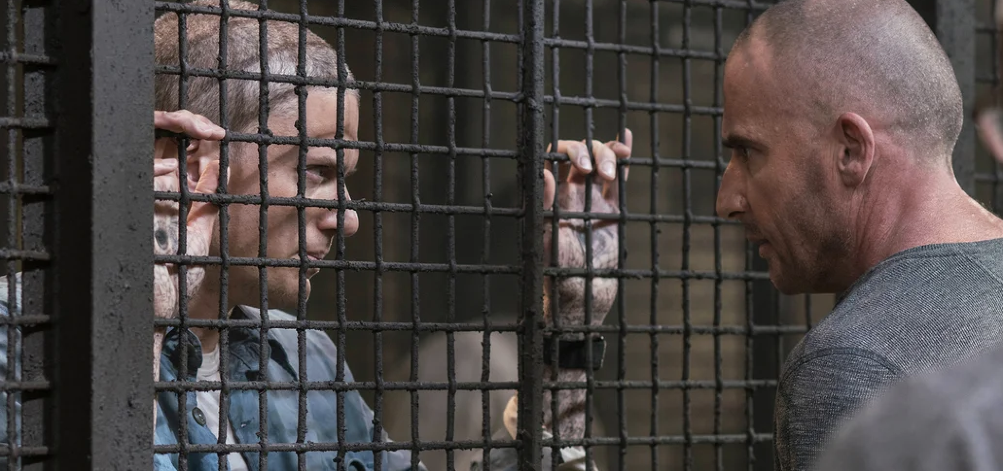 Wentworth Miller and Dominic Purcell in a tense scene, separated by a metal prison gate, from the TV series "Prison Break."