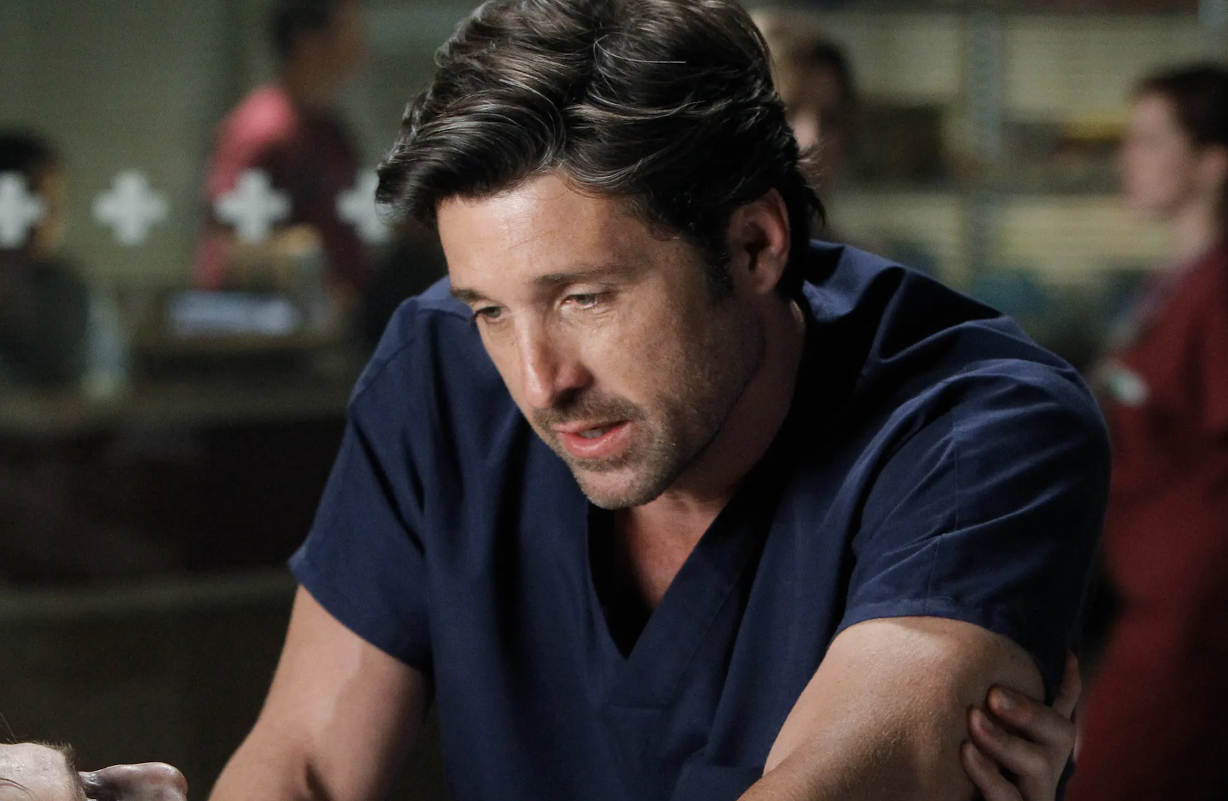 A man in blue medical scrubs appears deep in thought, possibly in a hospital setting. I don't know who he is