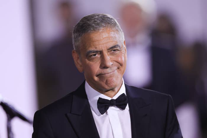 George Clooney in a formal dark suit and bow tie, smiling slightly at an event
