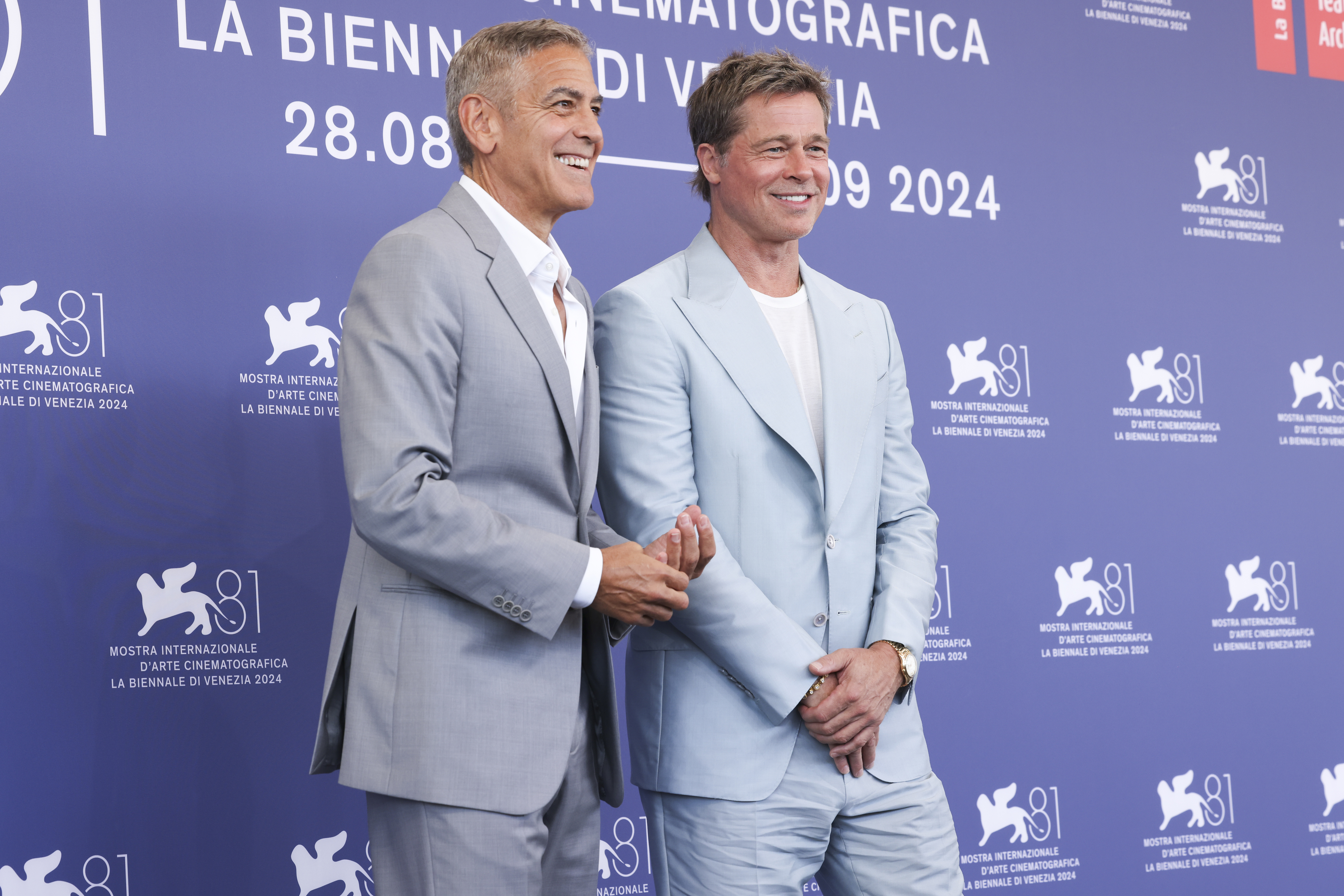George Clooney and Brad Pitt posing on the red carpet in suits at the Venice International Film Festival, 2024