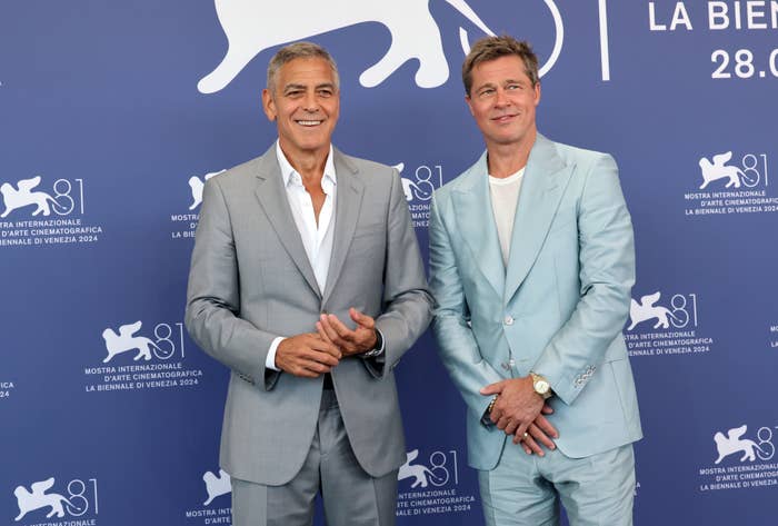 George Clooney and Brad Pitt at La Biennale di Venezia 2024, wearing stylish suits, smiling in front of a Venice Film Festival backdrop