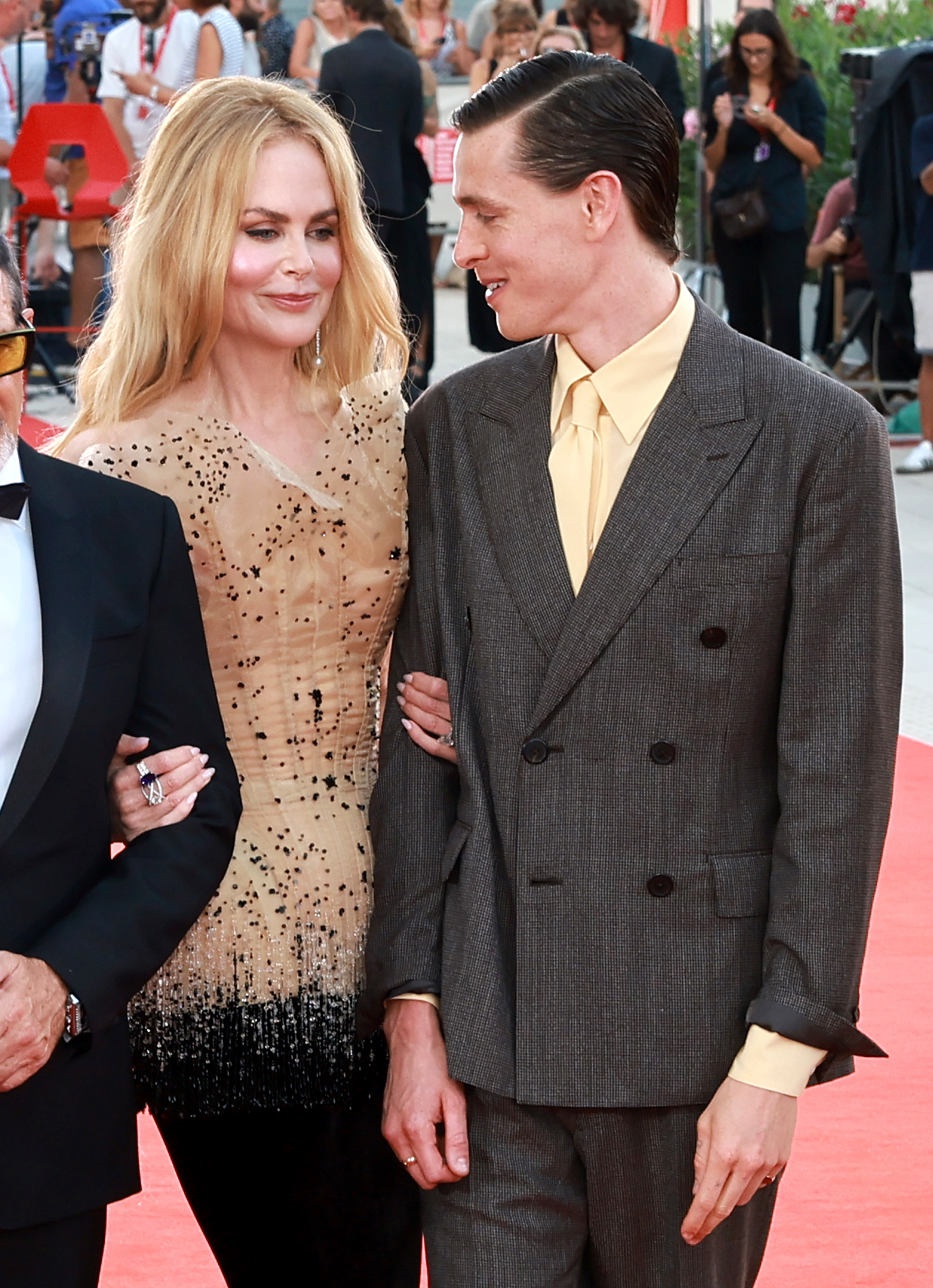 Nicole Kidman in a stylish dress, arm-in-arm with Matt Smith in a suit, walking on a red carpet at a public event