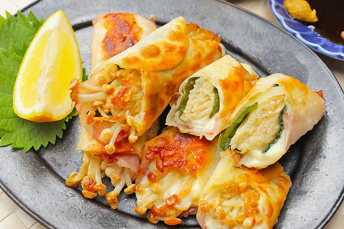 皿にレモンと数種類の餃子が盛られている。餃子には野菜とチーズが詰められており、焼き色が美味しそう。醤油の小皿と飲み物も写っている。