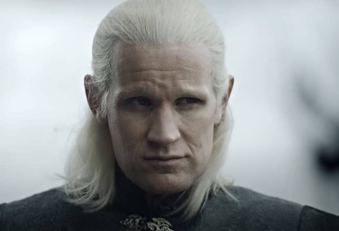 Matt Smith in &quot;House of the Dragon&quot; dressed in medieval-style attire with long, white hair, giving a serious expression