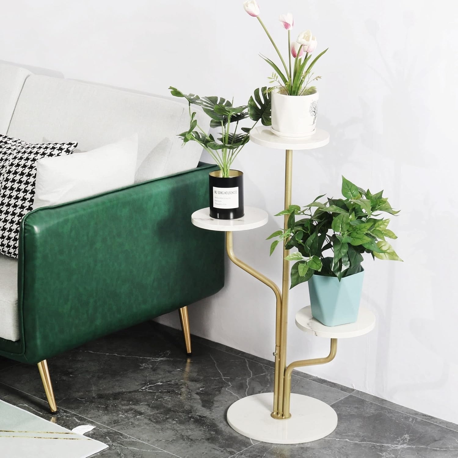 A modern living room corner with a green couch and a stylish multi-tiered plant stand holding various potted plants, including tulips and leafy greenery