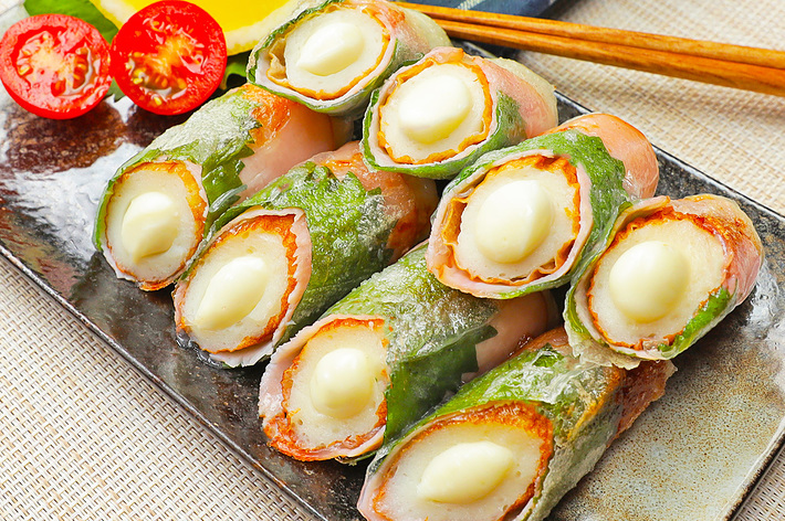 お皿に盛り付けられた、チーズを挟んだ肉巻きシソの揚げ物と半分に切ったプチトマトとレモンのスライス。