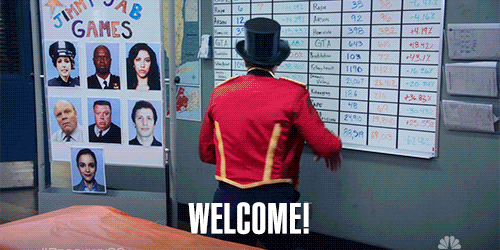 A man in a red jacket and top hat flips a whiteboard, revealing the word &quot;WELCOME!&quot; in large text while photos behind him show participants in the Jimmy Jab Games