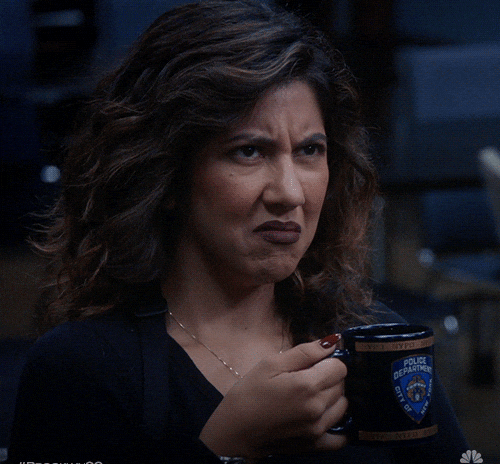 Stephanie Beatriz as Rosa Diaz in Brooklyn Nine-Nine looks skeptical while holding a police mug