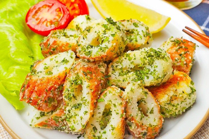 皿に盛られたちくわの唐揚げ、添え物としてレタス、トマト、レモン、木の箸。