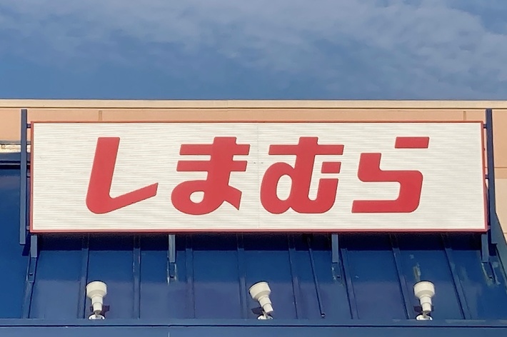 Storefront with a sign displaying Japanese characters. The building has a blue awning and a handicap accessible sign near the entrance