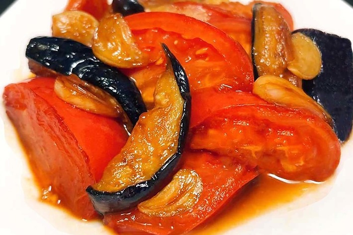 皿に盛り付けられたトマトやナス、にんにくの炒め物。