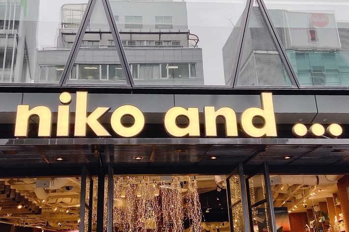 Storefront of &ldquo;niko and &hellip;&rdquo; featuring clothing and accessories inside, with a modern architectural design and visible display windows