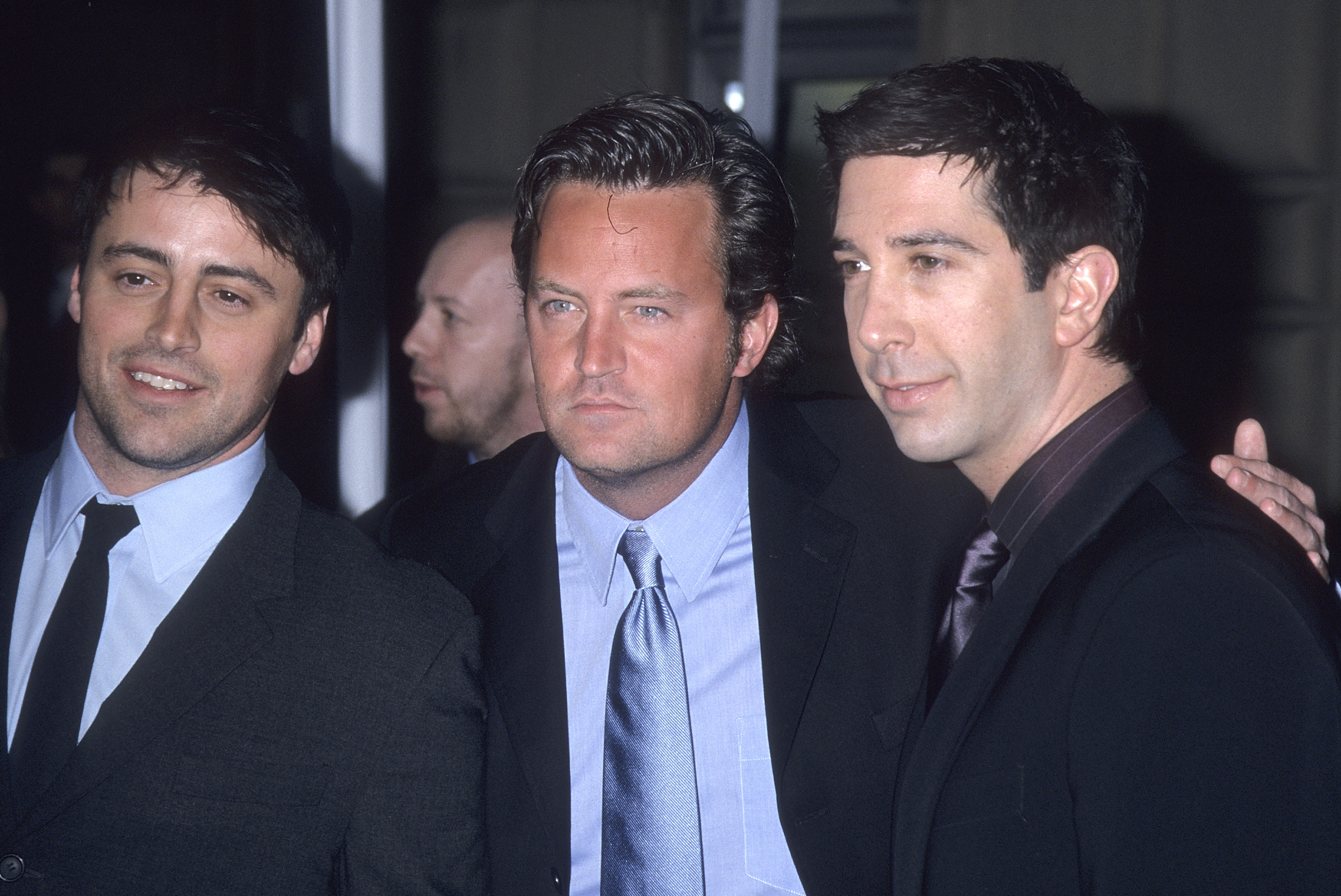 Matt LeBlanc, Matthew Perry, and David Schwimmer, all in suits, pose for a photo together at an event