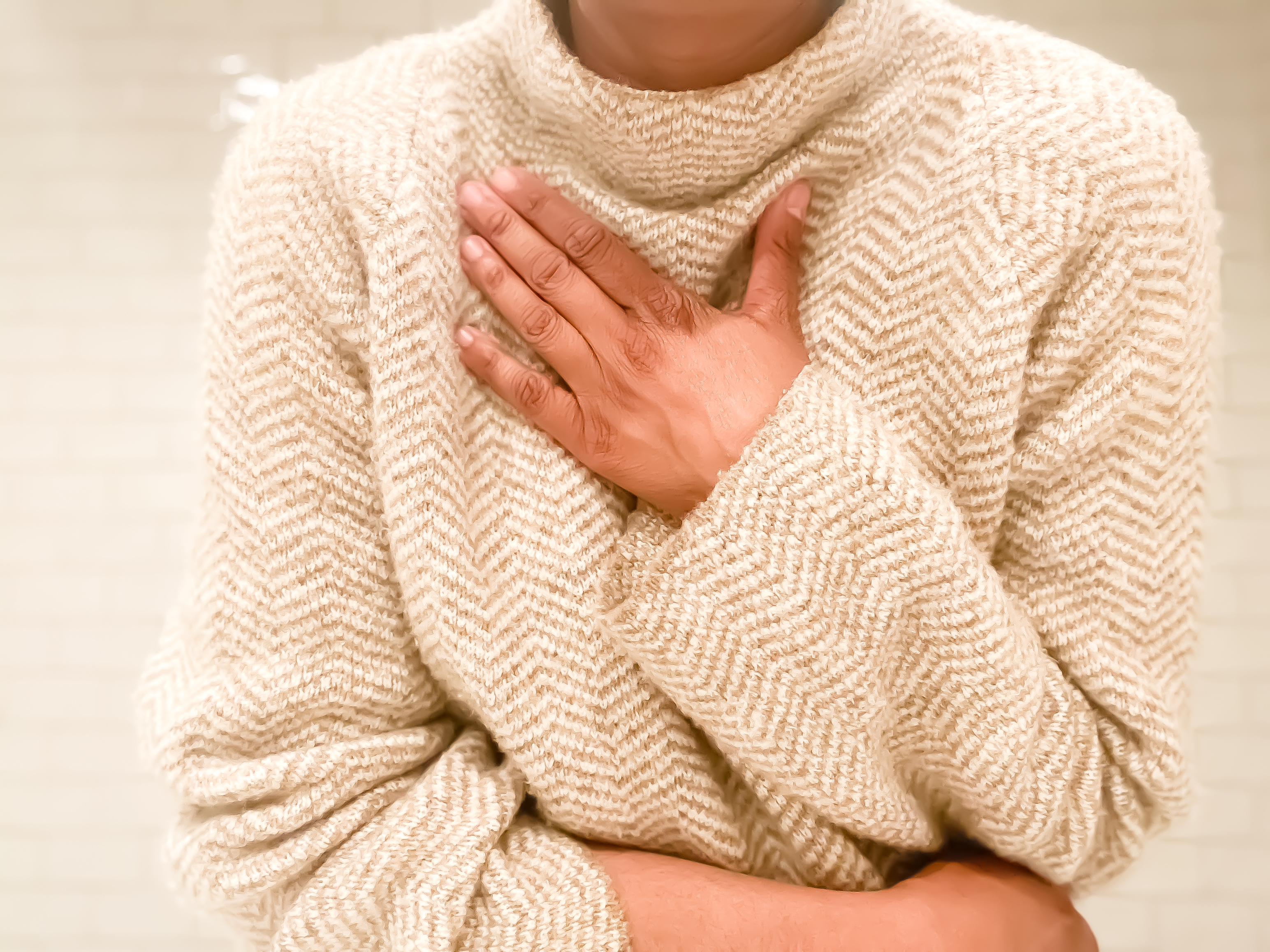 Person placing hand on chest; wearing a soft, textured sweater