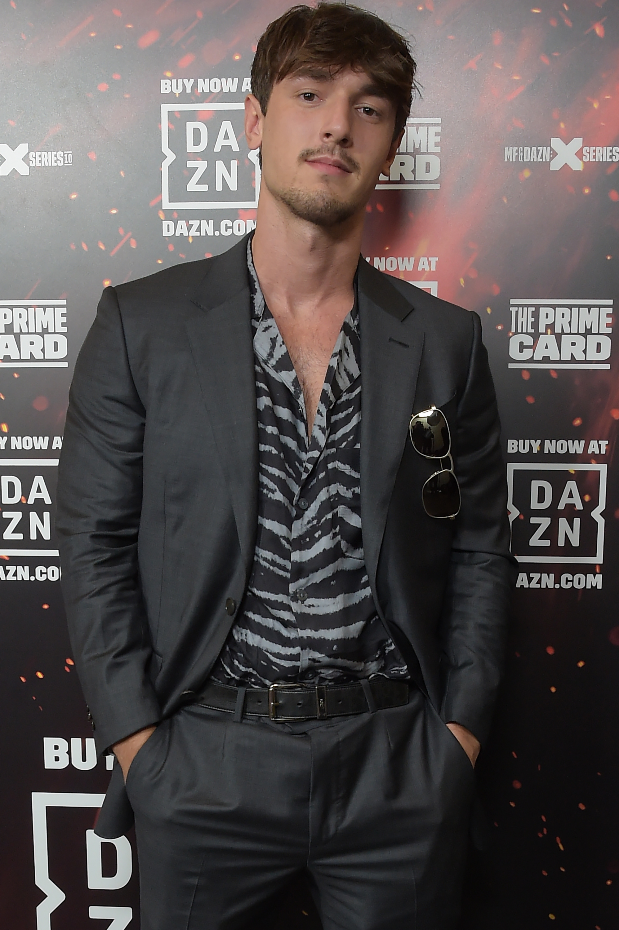 Bryce Hall poses on the red carpet wearing a suit jacket over a zebra-print shirt with sunglasses hanging from his shirt pocket