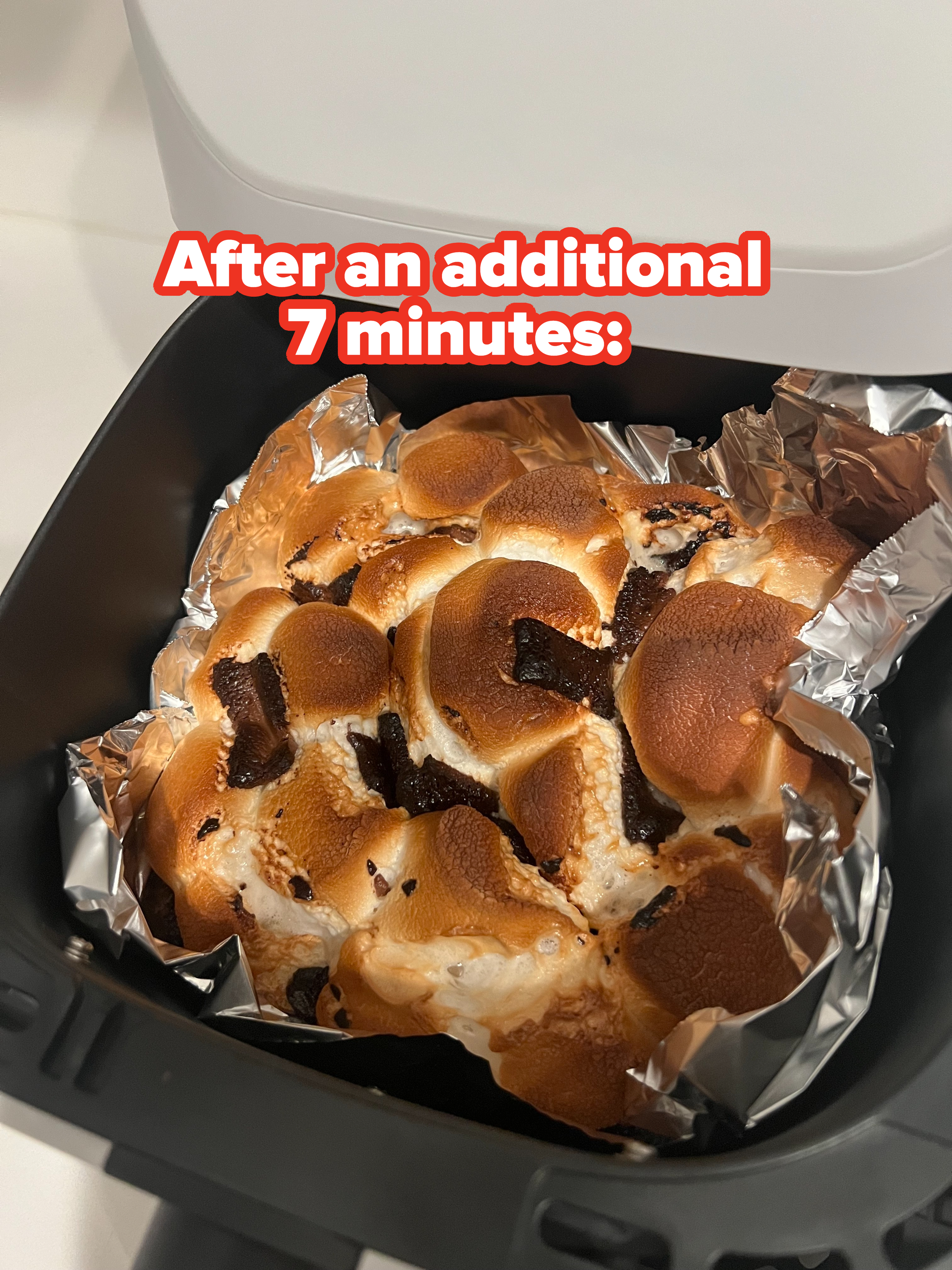 Toasted s'mores dip with melted marshmallows and chocolate chunks in a foil-lined air fryer basket