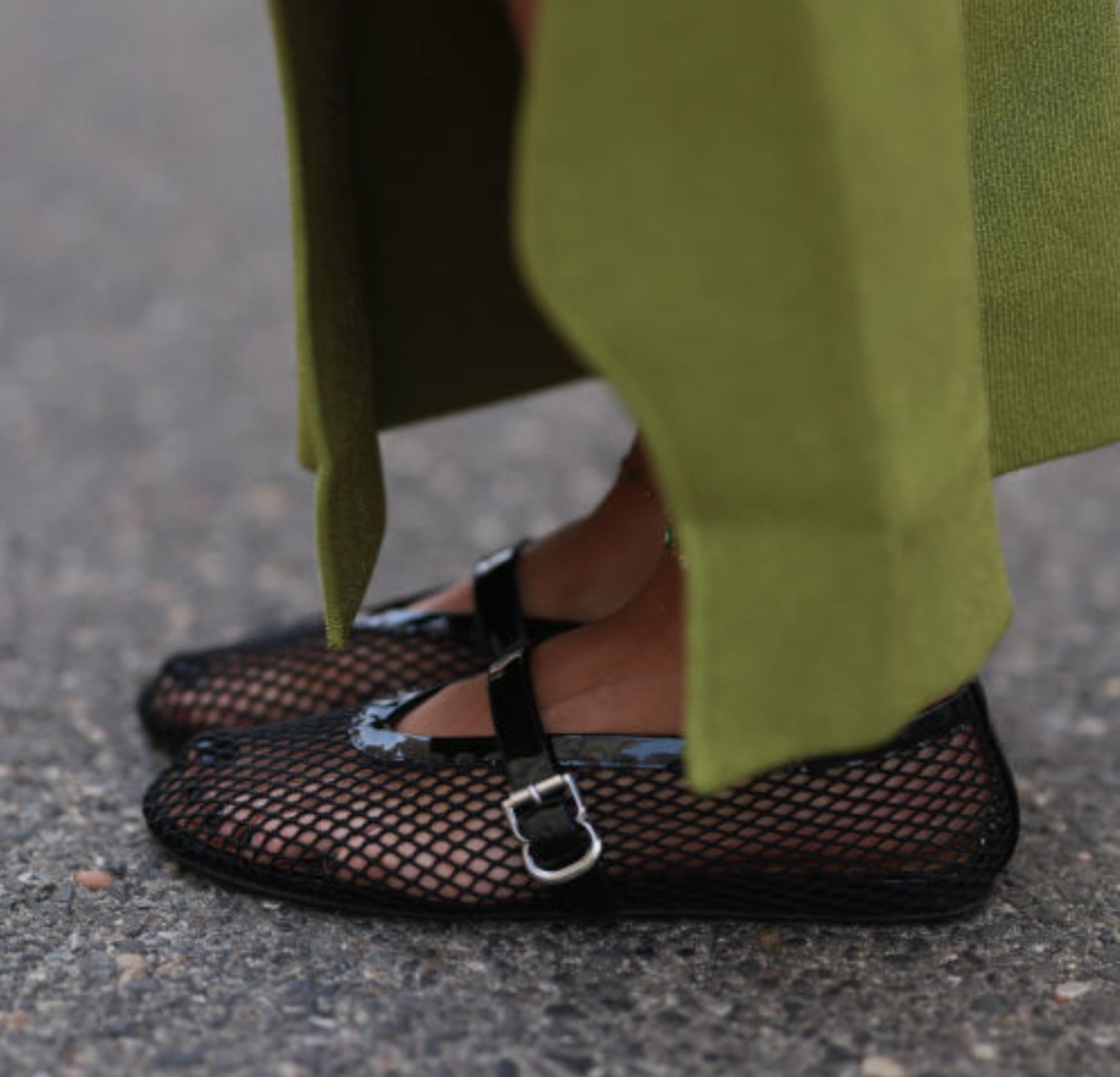 Mary Jane shoes with black mesh styling are worn by a person in a green skirt
