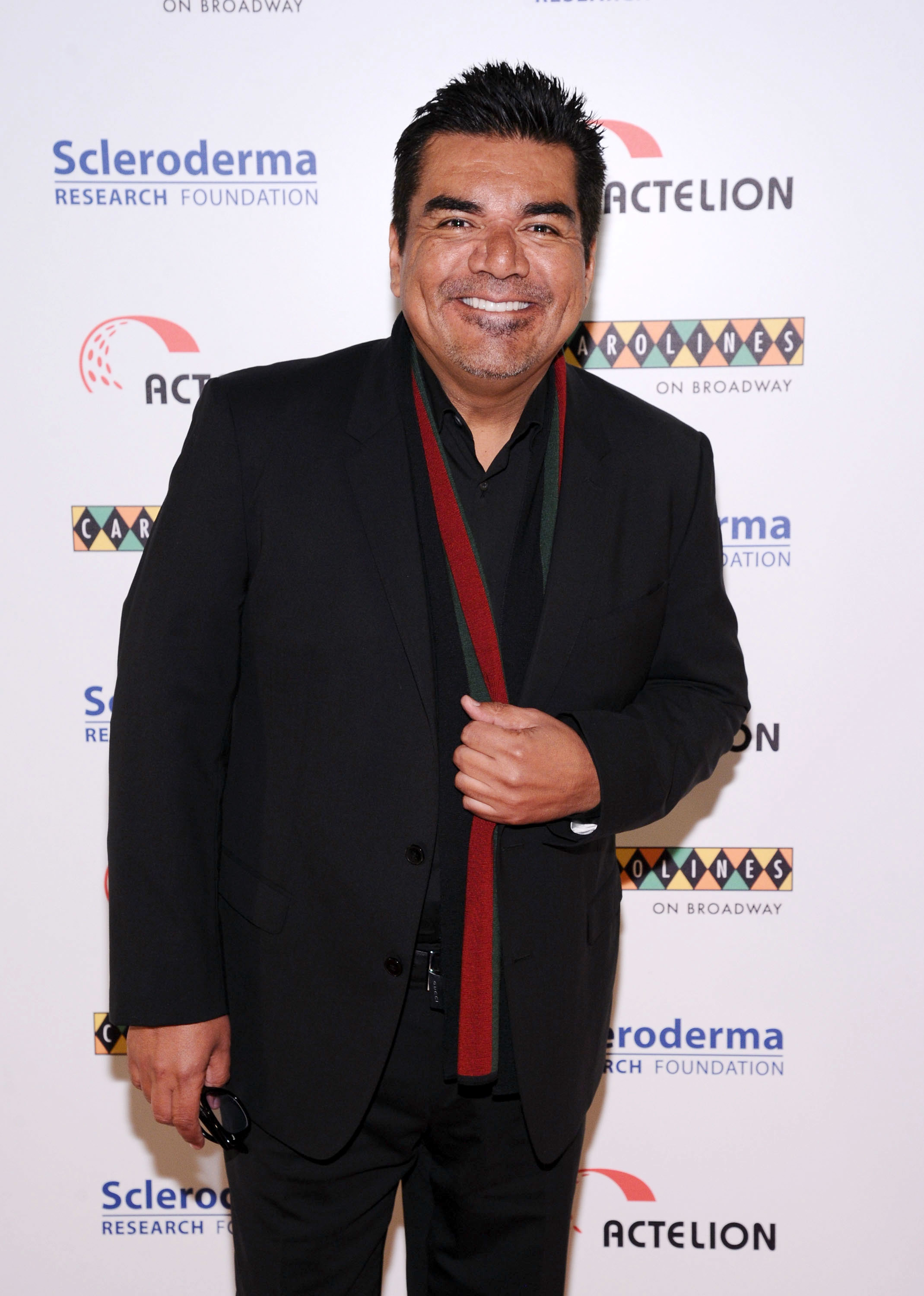 George Lopez in a black suit with an open red and green scarf at the Scleroderma Research Foundation event