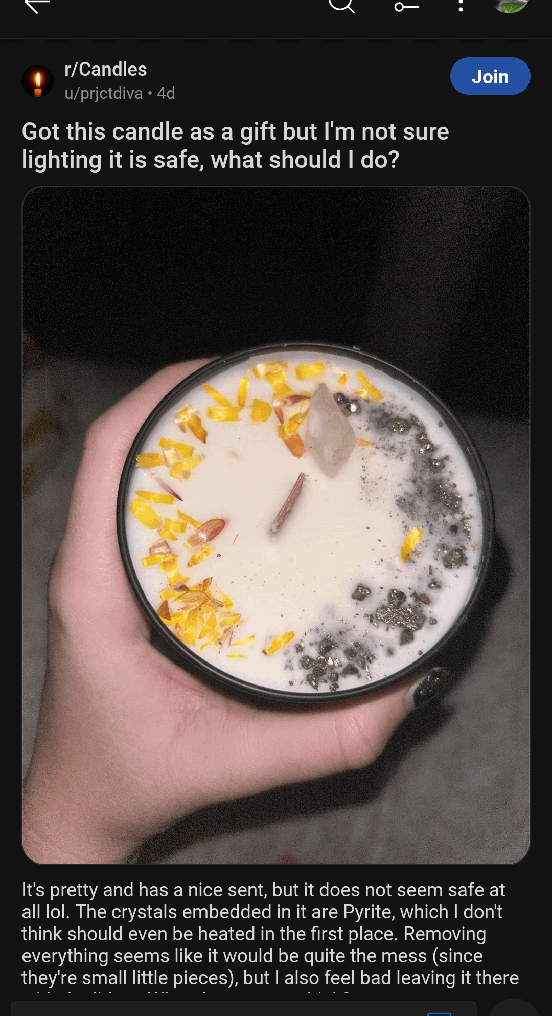 A person is holding a candle with crystals and yellow flower petals. The Reddit caption mentions the crystals are pyrite