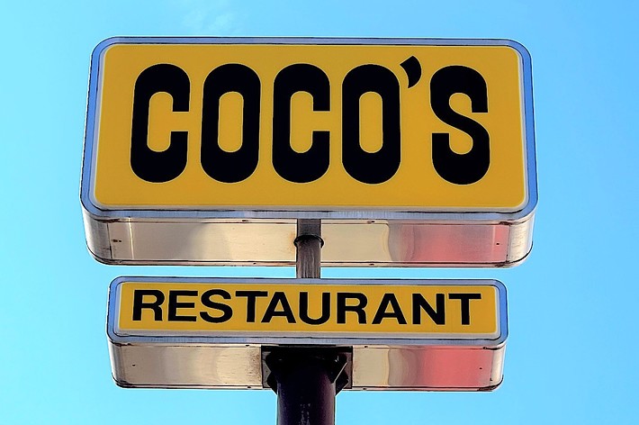A sign with the words &ldquo;COCO&rsquo;S RESTAURANT&rdquo; against a clear sky