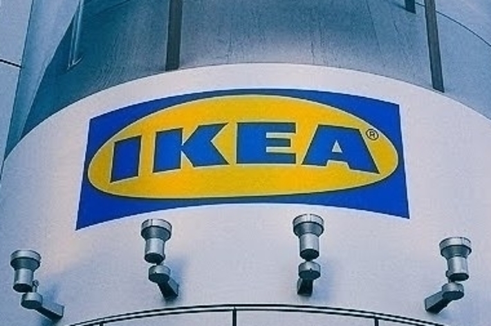 IKEAの看板が高層ビルの外壁に設置されている。看板の上には家具の広告が見える。