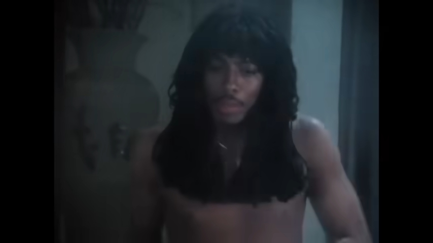 A shirtless Rick James with long hair in a scene from a music video