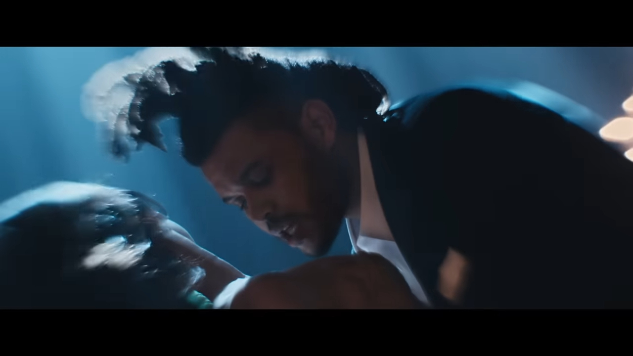 The Weeknd in an intimate romantic scene, leaning in close to a woman, the mood is intense and passionate