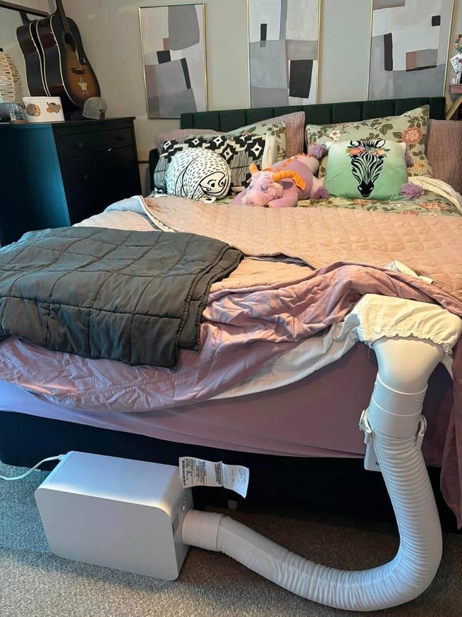 Bedroom with an unmade bed, decorative pillows, and a cooling appliance attached to the bed. Wall creation and guitars are disposable successful the background