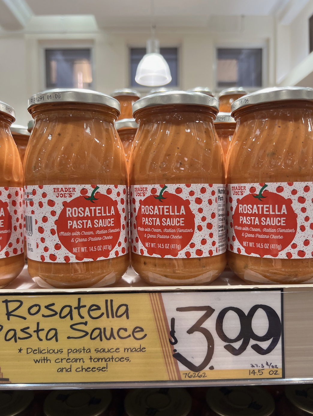 Three jars of Trader Joe's Rosatella Pasta Sauce are displayed on a store shelf. The shelf label reads "Rosatella Pasta Sauce - Delicious pasta sauce made with cream, tomatoes, and cheese!" The price is $3.99