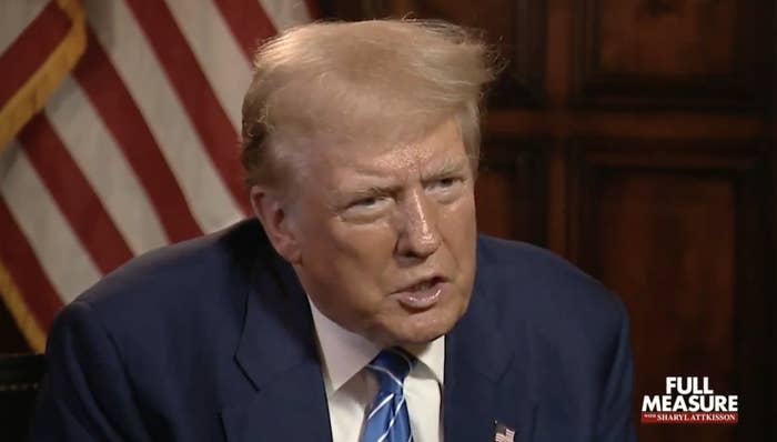 Donald Trump in a suit and tie, speaking during an interview for "Full Measure with Sharyl Attkisson." An American flag is partially visible in the background