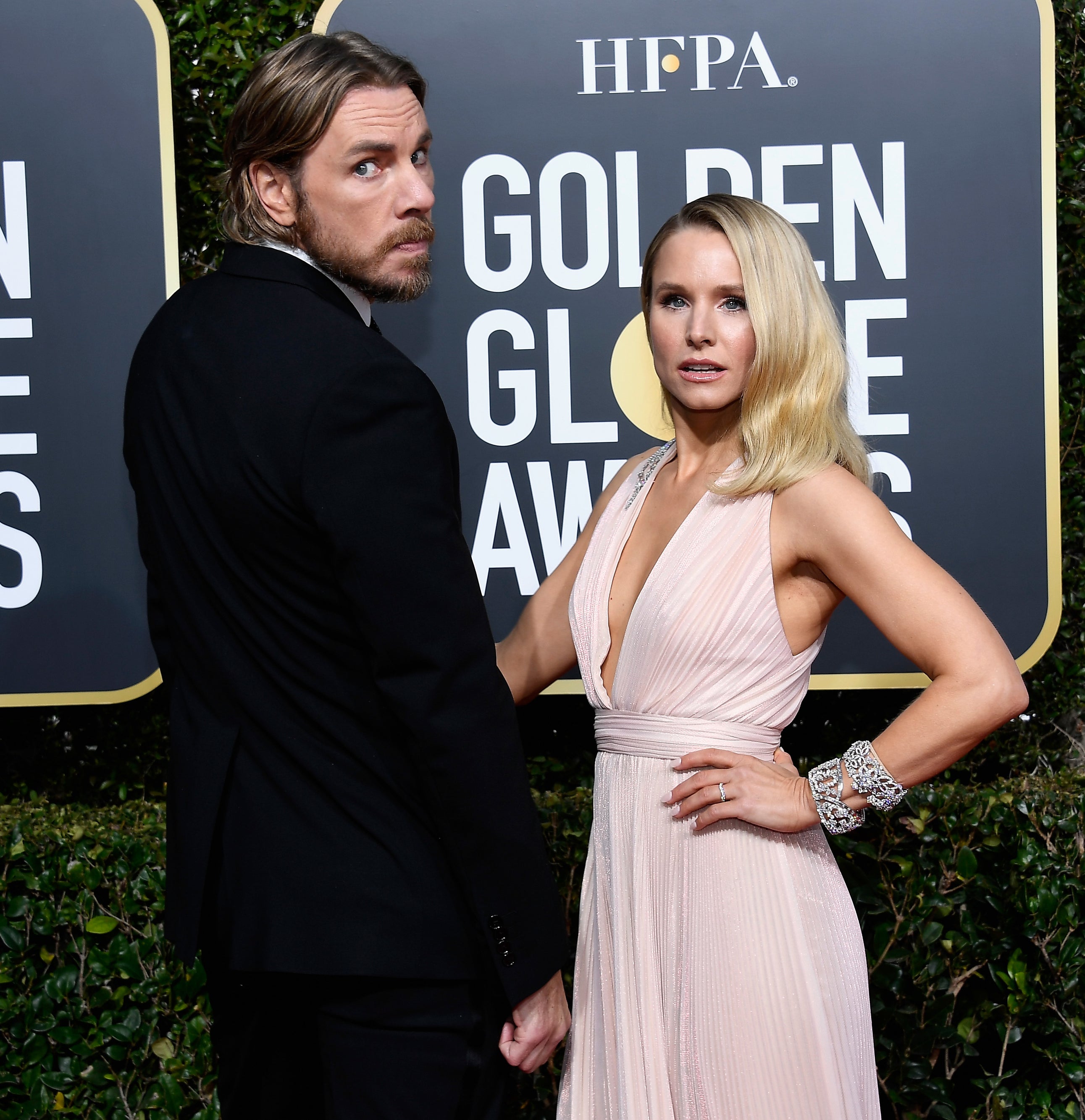 Dax Shepard and Kristen Bell on the red carpet at the Golden Globe Awards. Dax wears a black suit, and Kristen wears a flowing, sleeveless dress