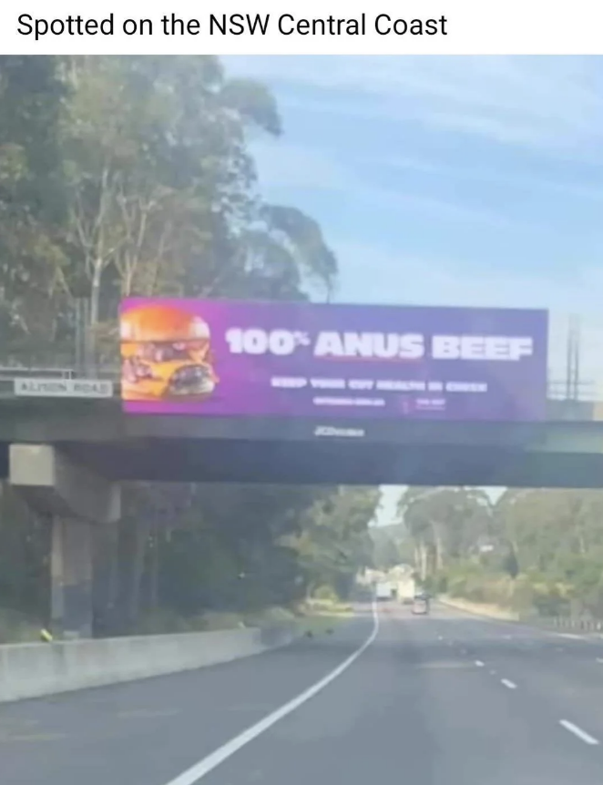 Billboard on the NSW Central Coast mistakenly displays "100% ANUS BEEF" instead of "100% ANGUS BEEF" above an image of a burger, causing amusement