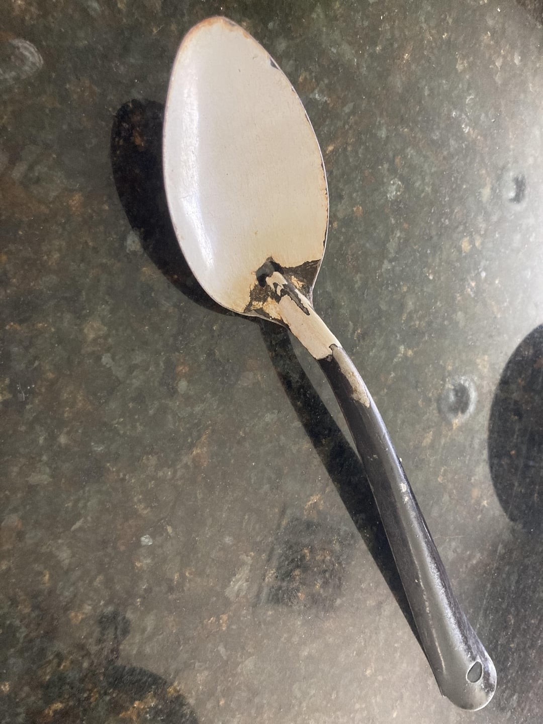 A metal spoon with a head that has been worn down and is now white instead of silver