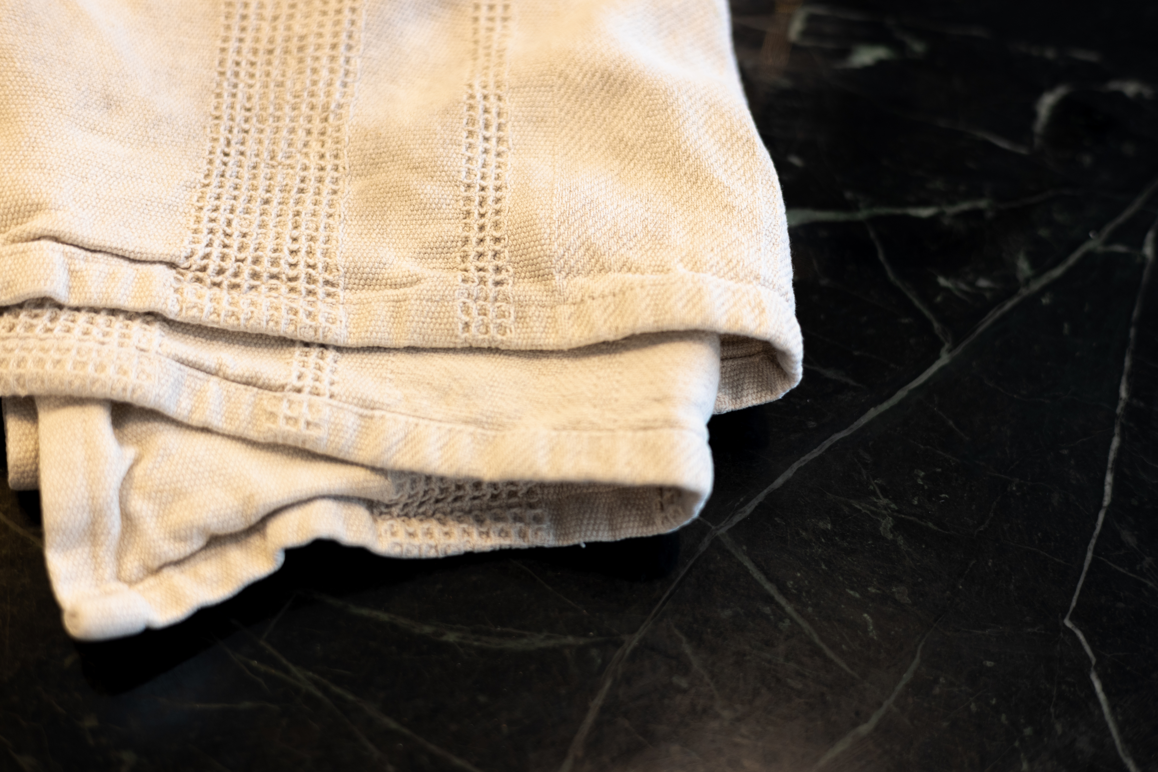 Folded fabric with intricate patterns rests on a dark marble surface. The image is used in an article categorized under Work &amp;amp; Money