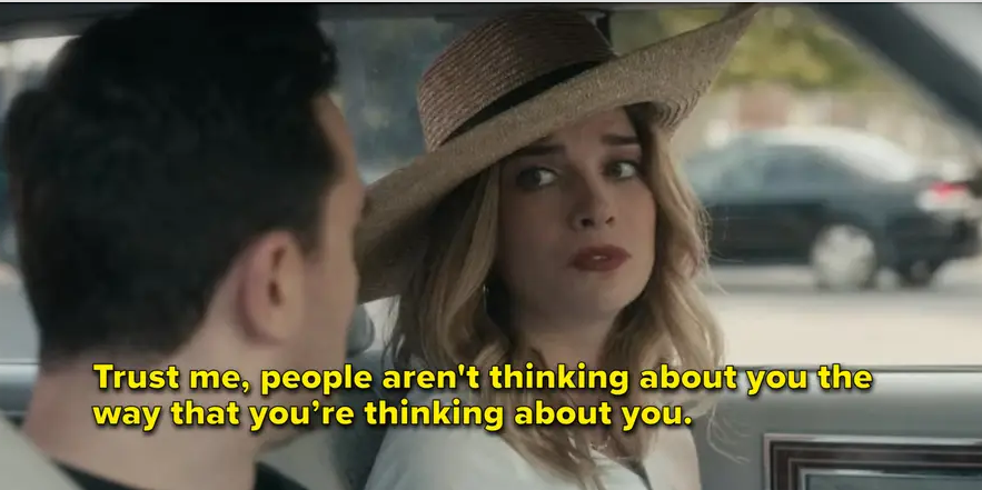 Two people in a car with a woman wearing a straw hat saying, "Trust me, people aren't thinking about you the way that you're thinking about you."
