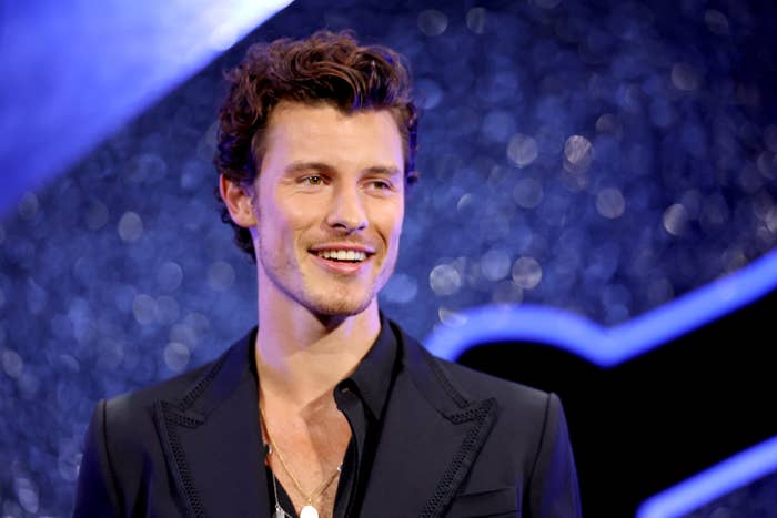 Shawn Mendes at an event, smiling and wearing a tailored suit