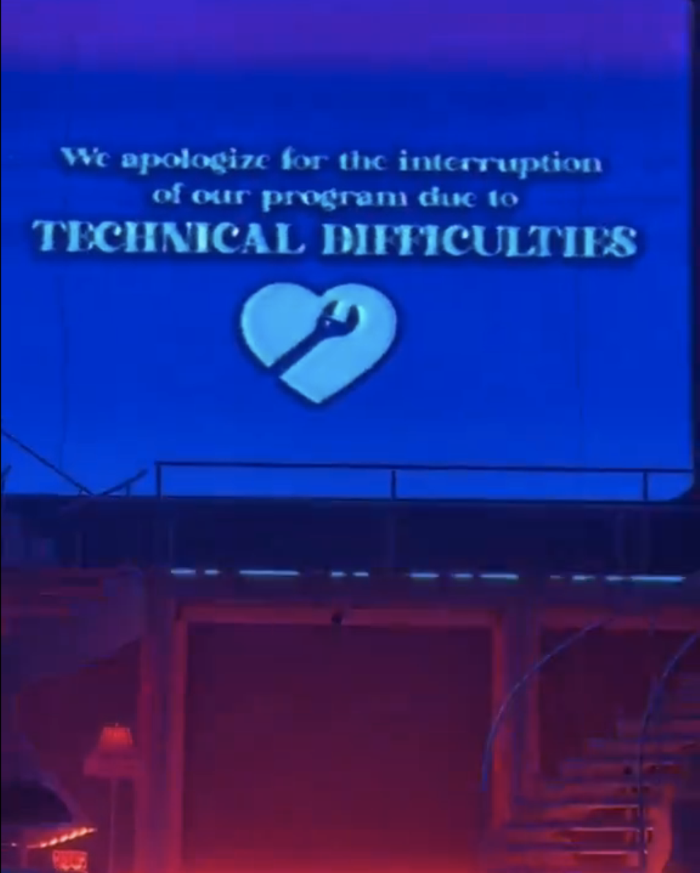 A message on a screen reads, &quot;We apologize for the interruption of our program due to TECHNICAL DIFFICULTIES&quot; with a wrench and heart icon