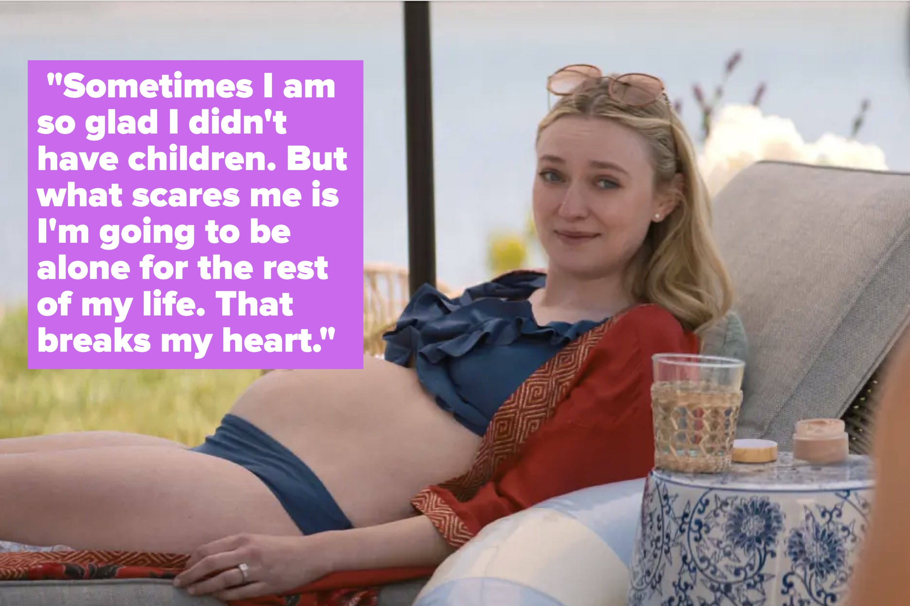 Dakota Fanning reclines on a lounge chair, displaying a pregnant belly, wearing a black bikini top and red shawl. Outdoor setting by the water