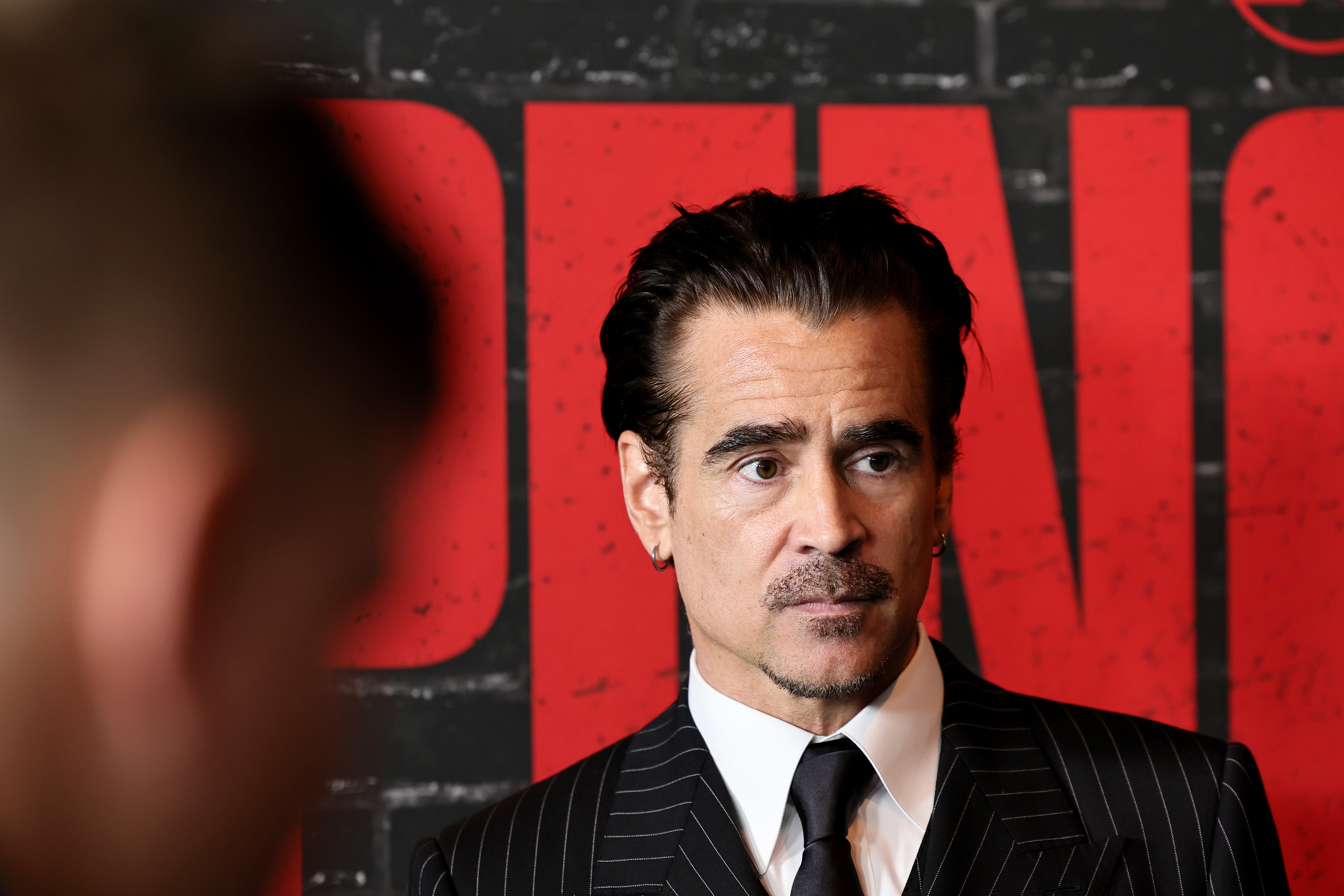 Colin Farrell in a pinstriped suit and tie at a red carpet event