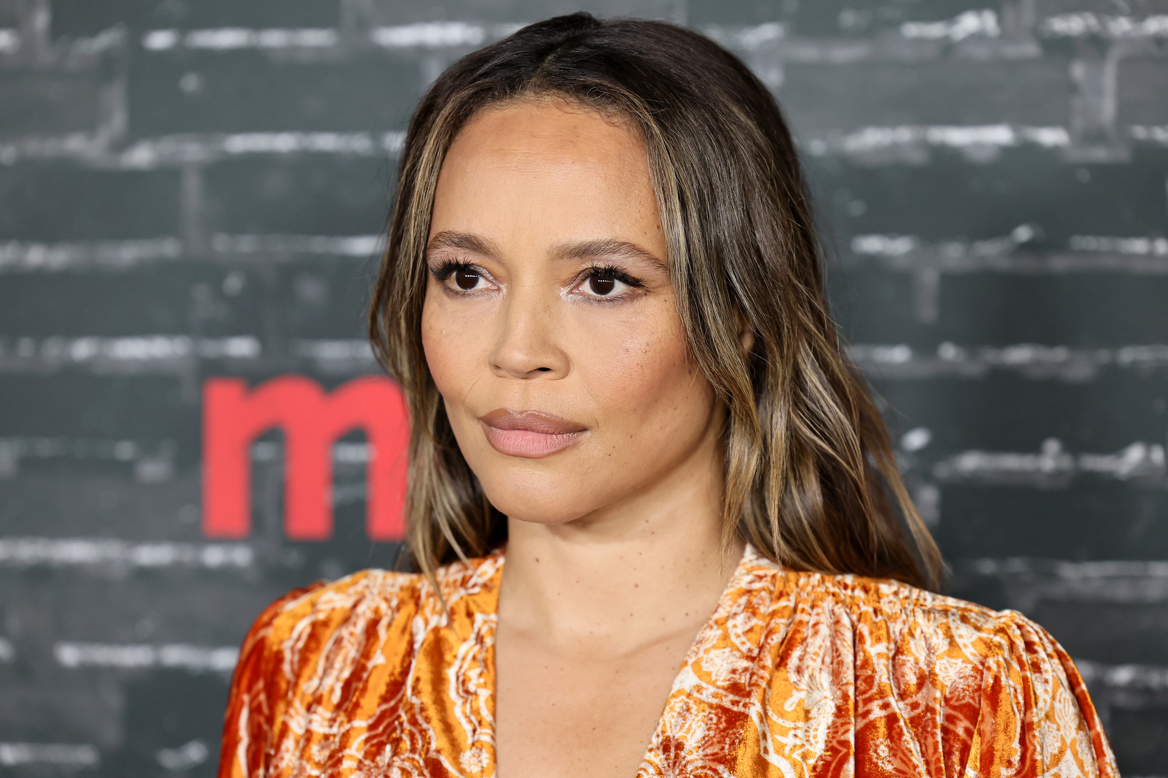 Carmen Ejogo poses in an orange patterned outfit at a TV and Movies event