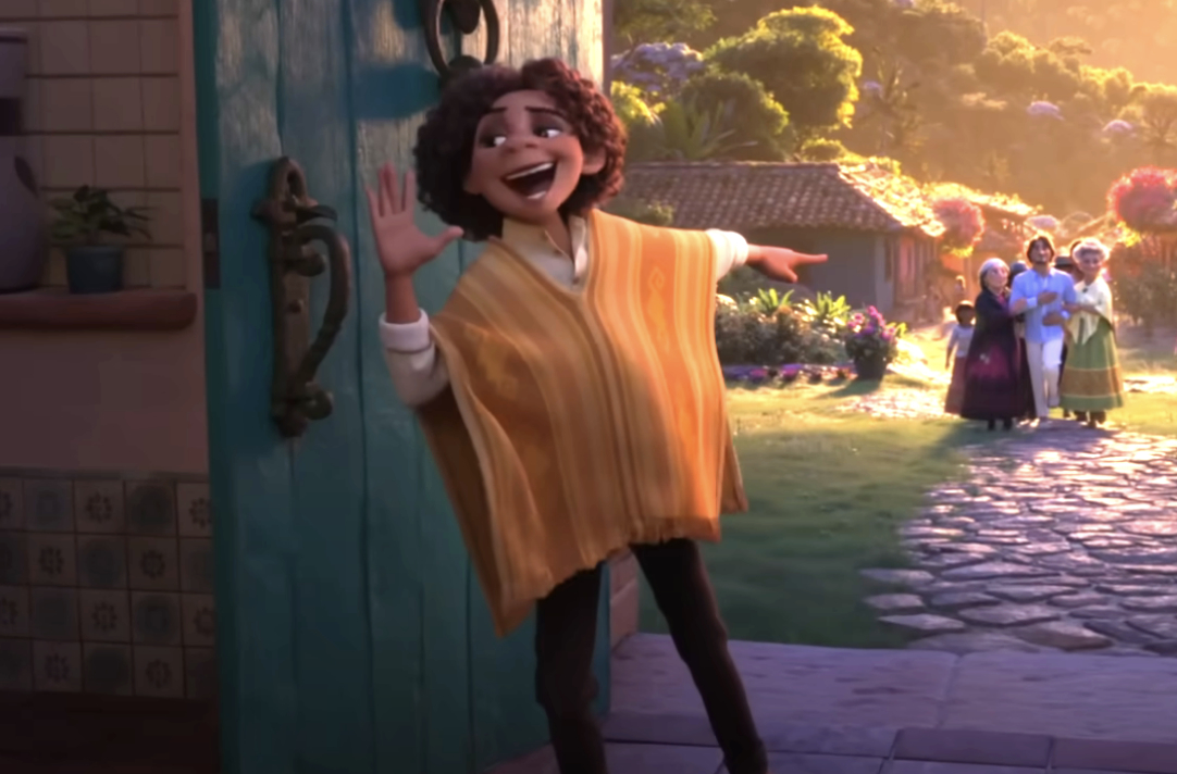 Antonio Madrigal smiling and waving by a door, with villagers in the background in a scene from Encanto
