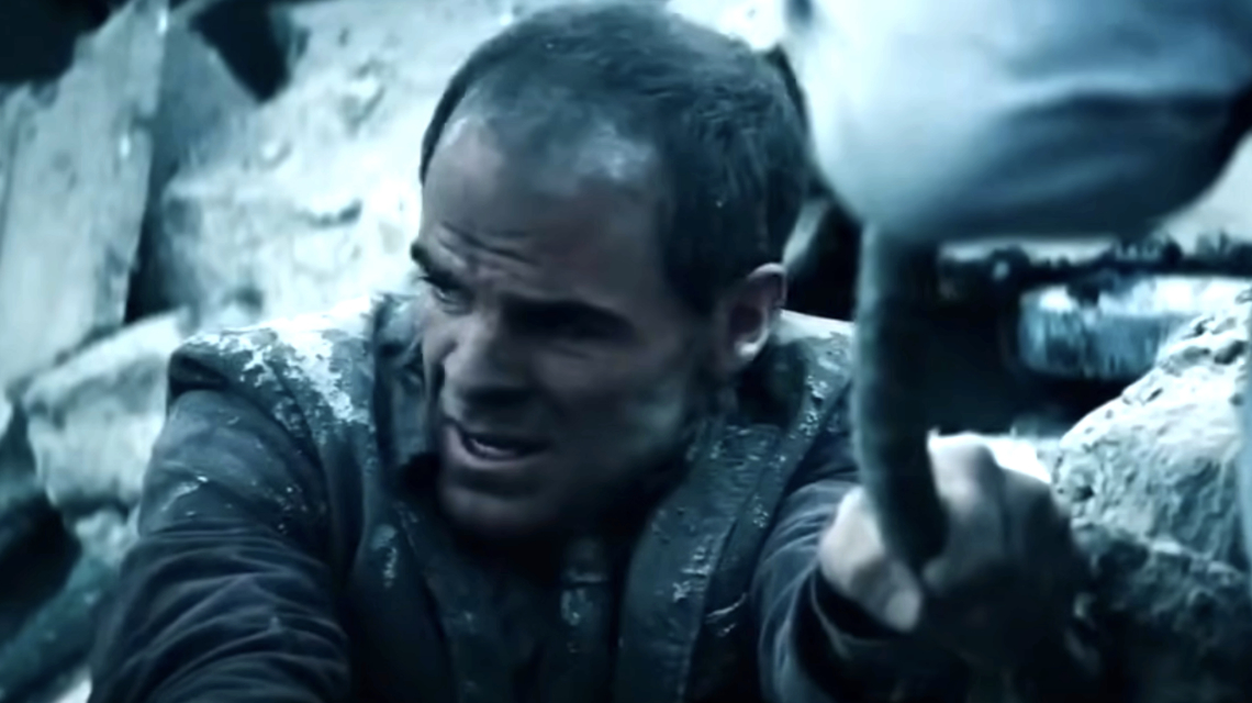 The image shows a man named Steve Lombard struggling amidst the rubble, reaching out while looking determined