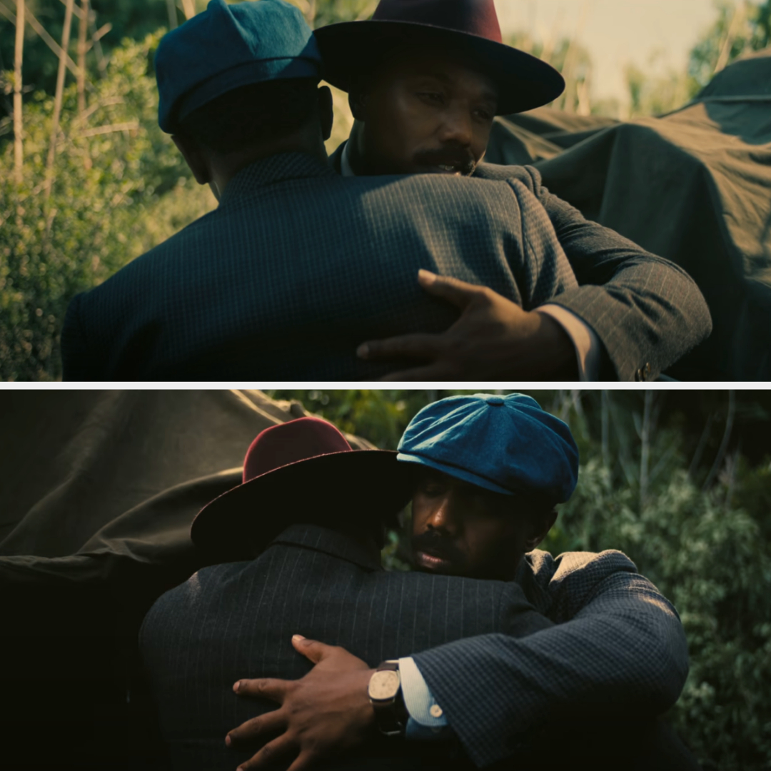 Twin brothers, played by Michael B. Jordan, share an emotional embrace in a scenic outdoor setting, both wearing stylish, vintage-style hats and suits