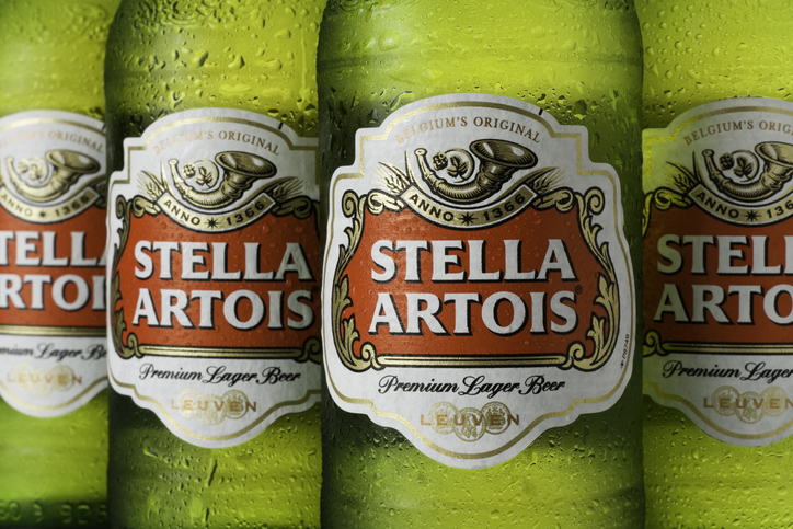 Close-up of four Stella Artois beer bottles lined up, showcasing their labels with the brand's name prominently displayed