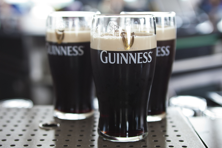 Three pints of Guinness on a table in a bar setting. No people are visible in the image