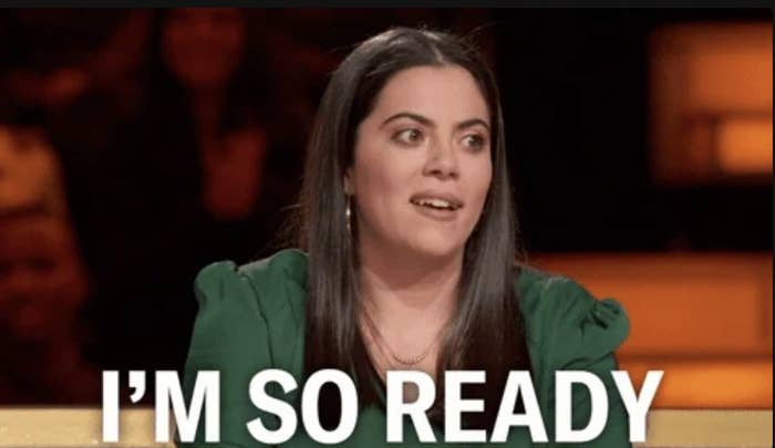 A woman with long dark hair is seated indoors, looking ahead and smiling slightly. The text over the image reads "I'M SO READY."