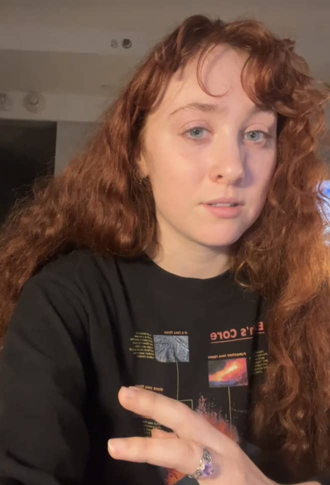 Chappell Roan with long, wavy hair wears a graphic T-shirt, looking at the camera with a neutral expression