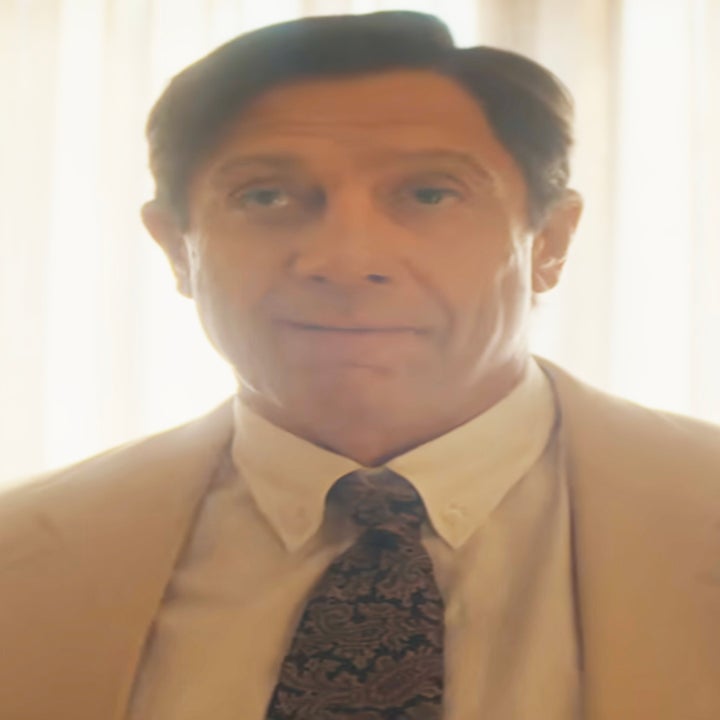 Javier Bardem as José Menendez in a suit and tie stands indoors with light streaming in from behind