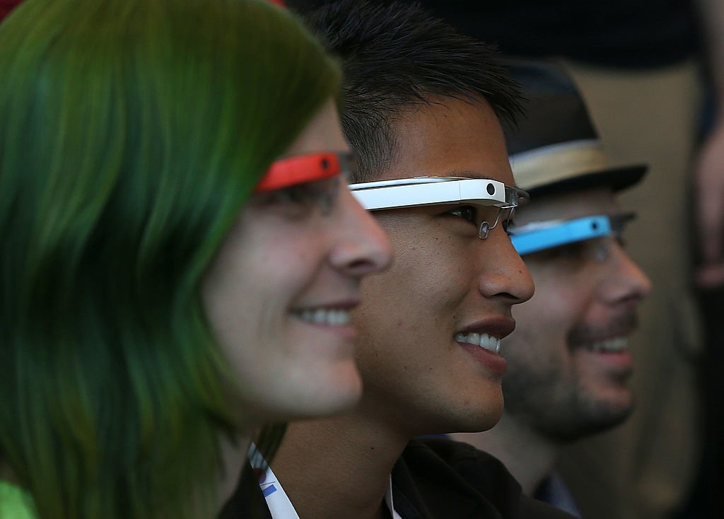 Three people wearing Google Glass smile while looking at something off-camera